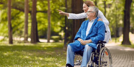 A nurse walking taking a senior man on a walk outdoors