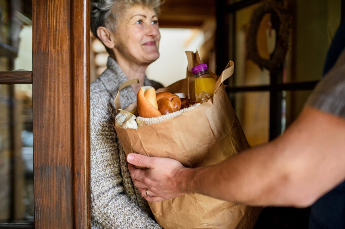 volunteer delivering groceries to a senior woman