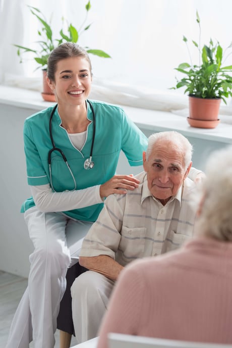 Happy nurse hugging senior patient in nursing home