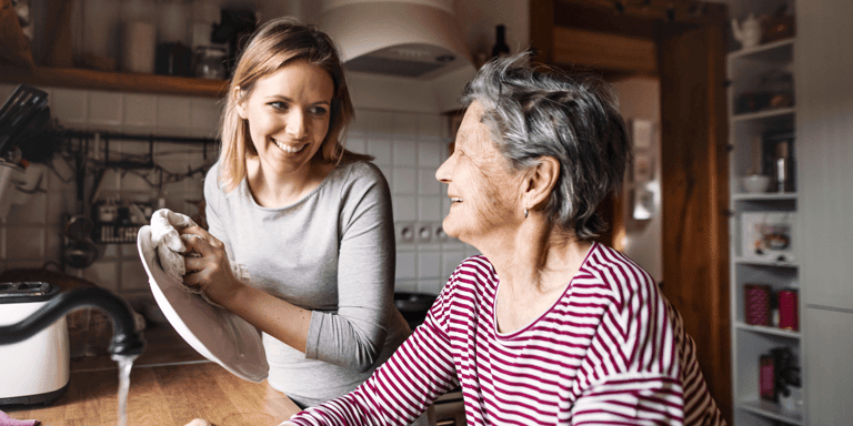 A  grandmother with an adult granddaughter at home, washing the dishes