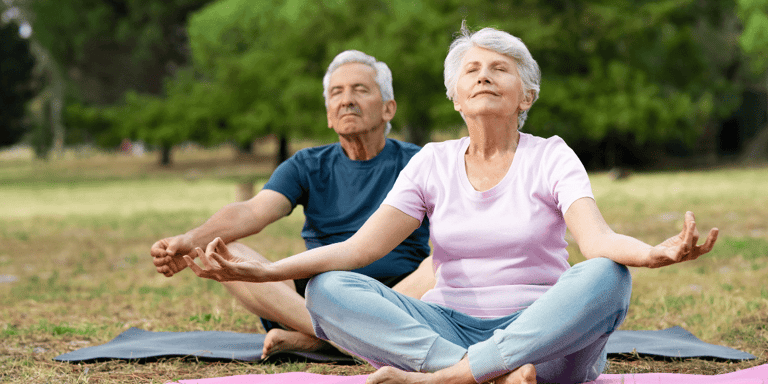 A couple doing yoga for seniors in the park