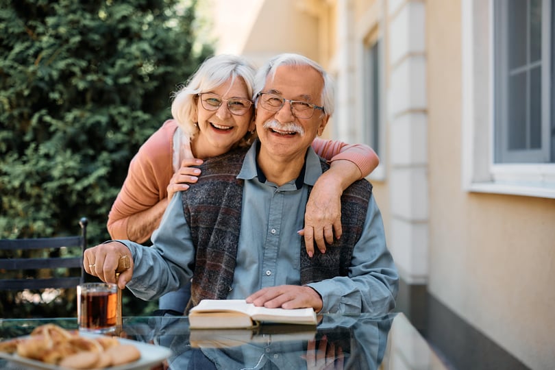 A happy senior couple having a meal on a patio at an independent living community