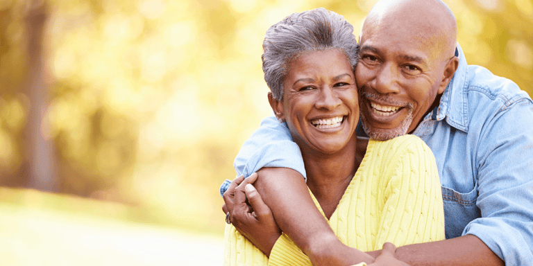 A senior couple relaxing and smiling in front of an autumn landscape