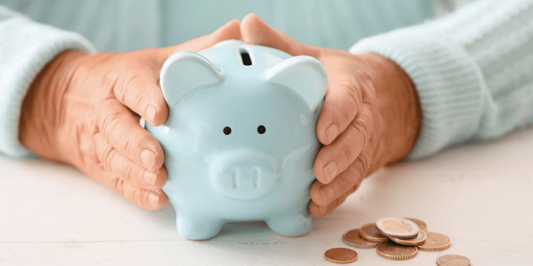 An older woman holding a piggy bank at a table