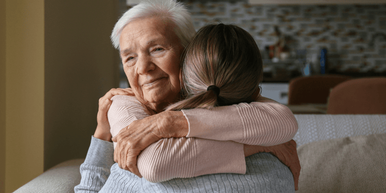 Senior woman hugging caregiver at home