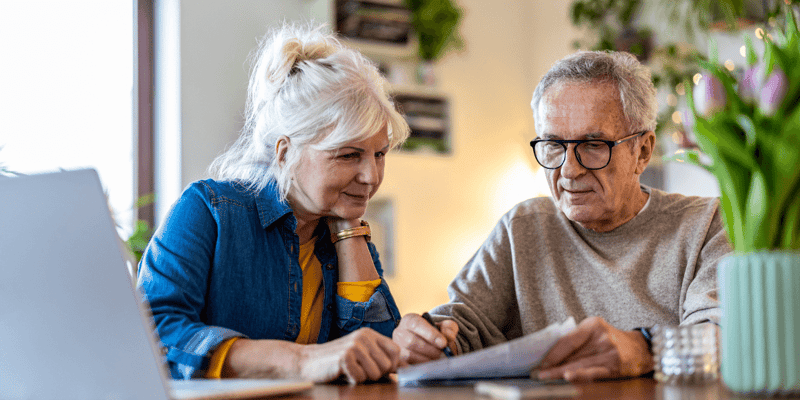 A senior couple sitting at a table and discussing their finances