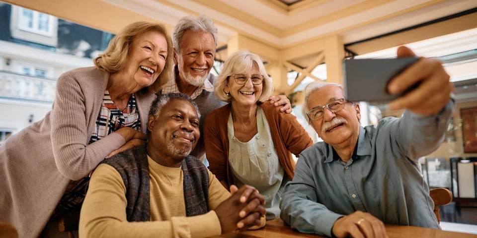 Senior friends having fun playing cards and taking a selfie