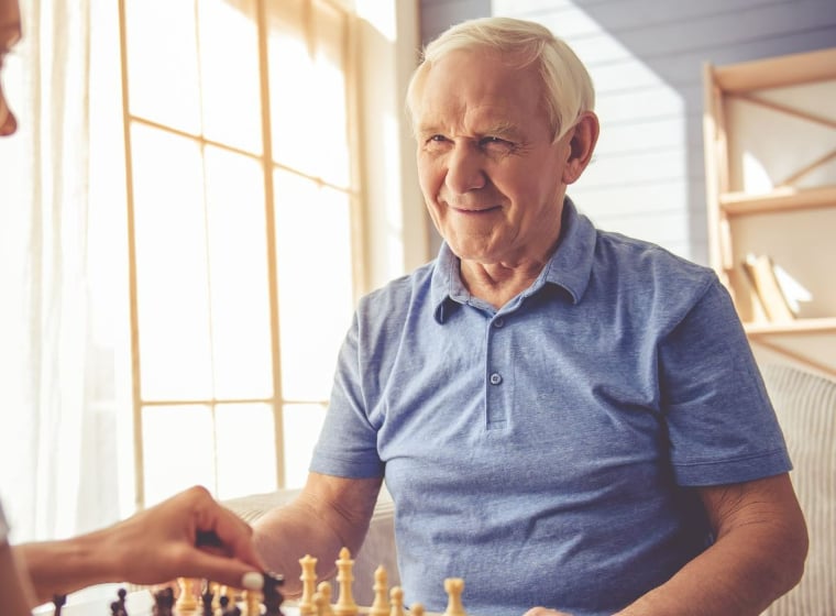 senior man playing chess with a caregiver