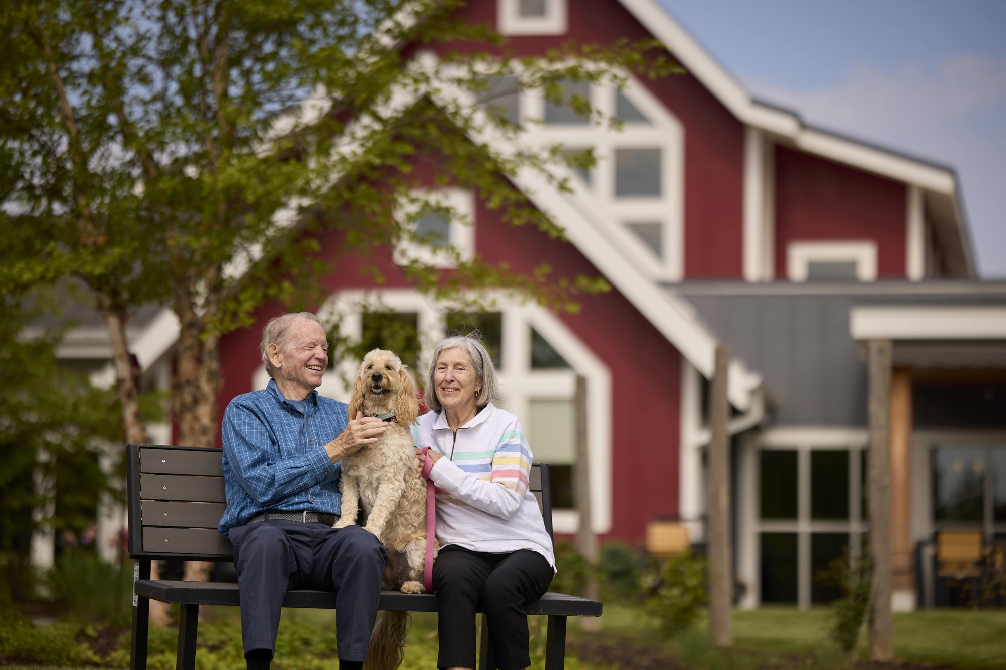 Senior couple with their happy dog smiling on a bench