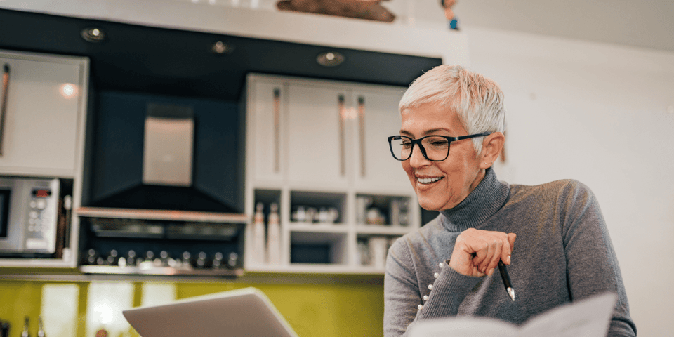 A happy older woman reviewing independent living costs on her laptop.